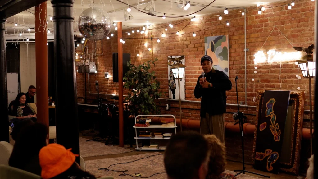 Chad Chambers speaking to an audience in an intimate brick-walled venue
